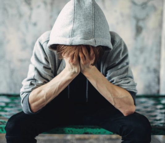 Hoe herken je een verslaving bij jezelf? Verslaafde zit met handen in het haar