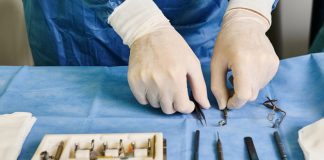 Wanneer is specialistische chirurgische zorg nodig en wat houdt het in Man met witte handschoenen legt gereedschap voor operatie klaar