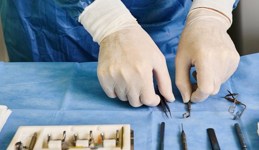 Wanneer is specialistische chirurgische zorg nodig en wat houdt het in Man met witte handschoenen legt gereedschap voor operatie klaar