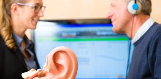 Je gehoor verbeteren begint met een test Vrouw voert gehoor test uit bij man