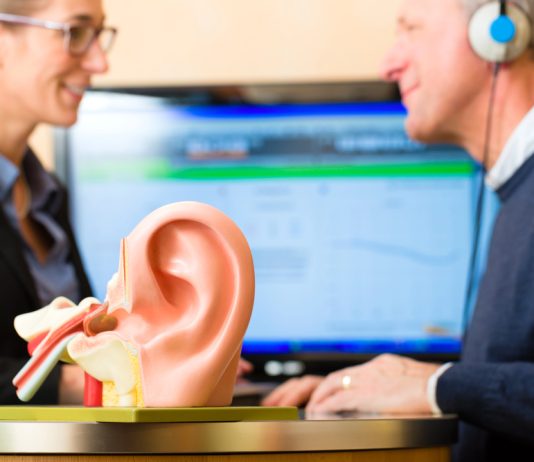 Je gehoor verbeteren begint met een test Vrouw voert gehoor test uit bij man