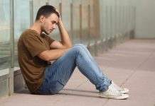 Deze maatregelen zorgen voor minder depressies onder jongeren Tienerjongen kijkt bezorgd en zit op de grond