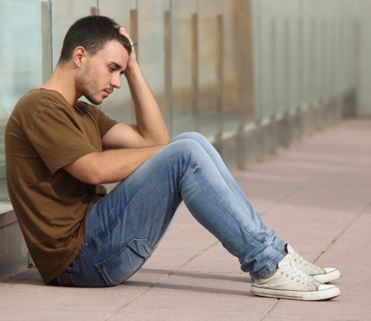 Deze maatregelen zorgen voor minder depressies onder jongeren Tienerjongen kijkt bezorgd en zit op de grond